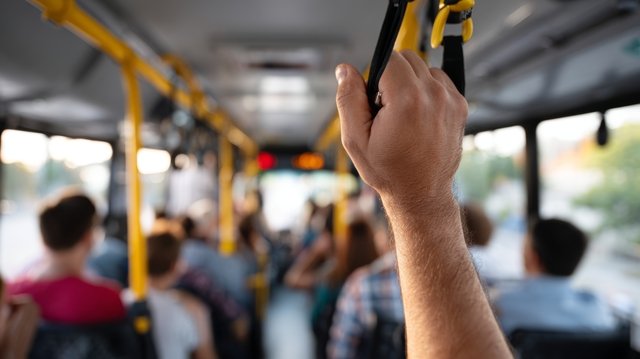 Passenger gripping a bus handrail illustrating 8 ways charter buses enhance your journey